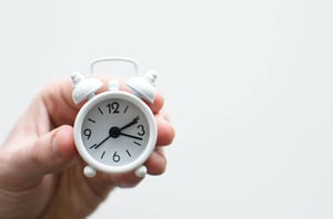 hand holding small white clock