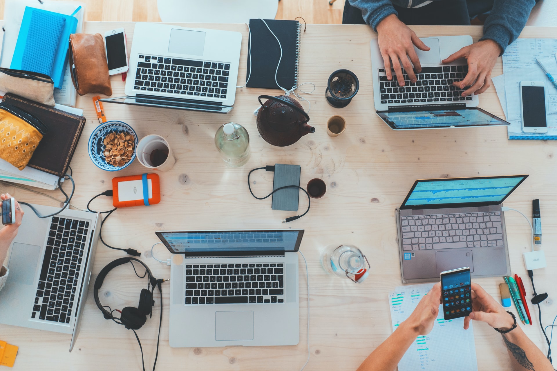 overhead view of table full of computers, phones, and headphones